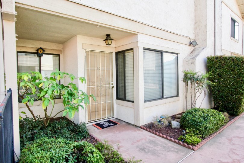 a house entrance with a welcome mat with skull, loosely maintained bushes and a decent look