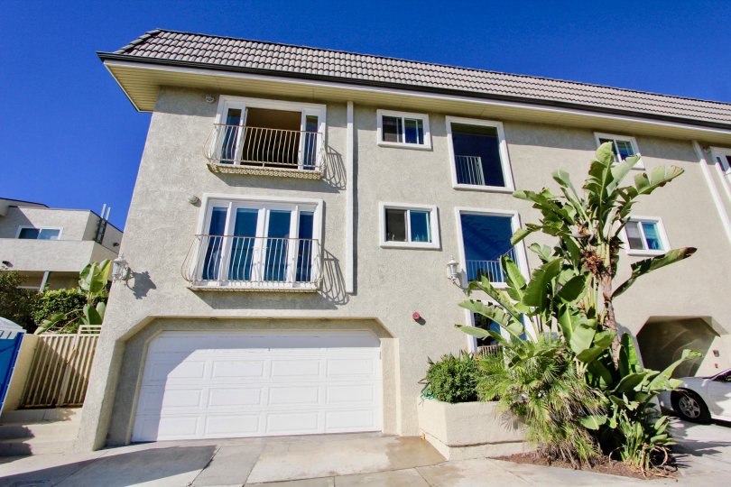 3 storey apartment complex with palm trees and garage space