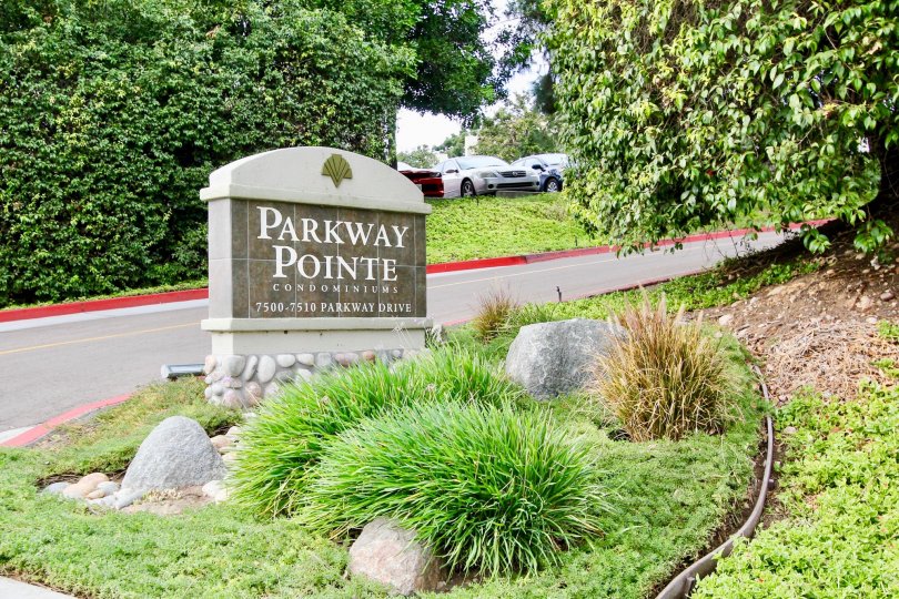 a sign in the Parkway Pointe with lot of plants and vehicles.