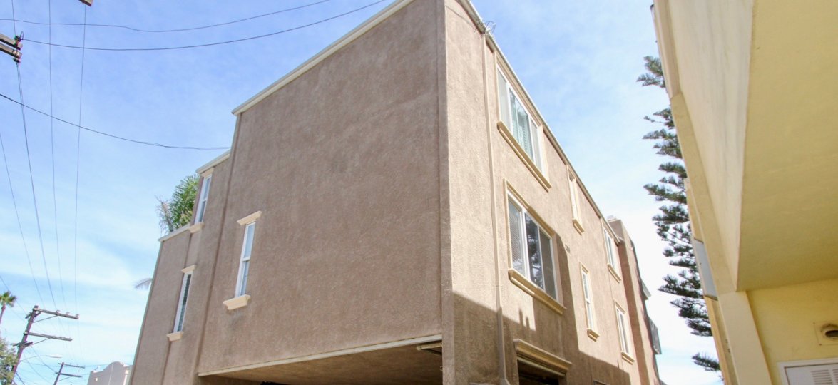 The stucco exterior of the Bayfront Youngson apartment building showing the private car port, and two stories of apartments.