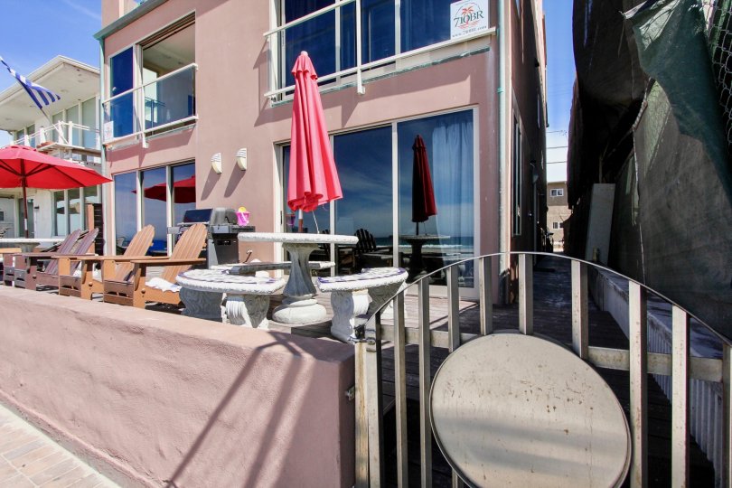 A deck with tables, chairs, and umbrellas by the Jersey community in Mission Beach, CA