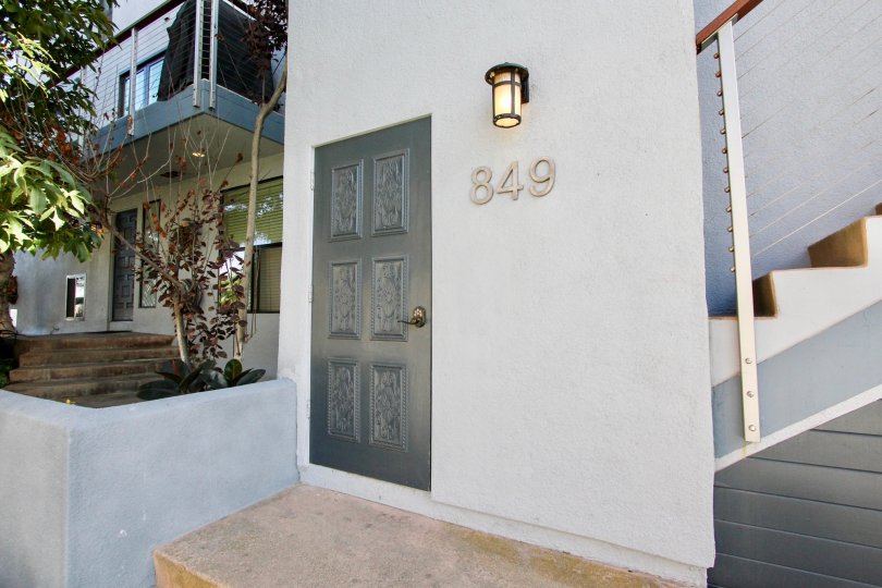A doorway for a property in Mission Shores with a lamp and landscaping