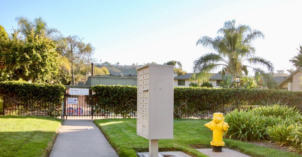 A view of the grounds at the Mission Playmor grounds which shows the community mailbox and fence around the swimming pool.