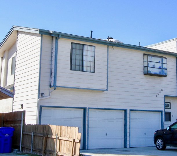 A home located in North Court community in Normal Heights, California. Shows three garage doors, the siding of the house, and a window.