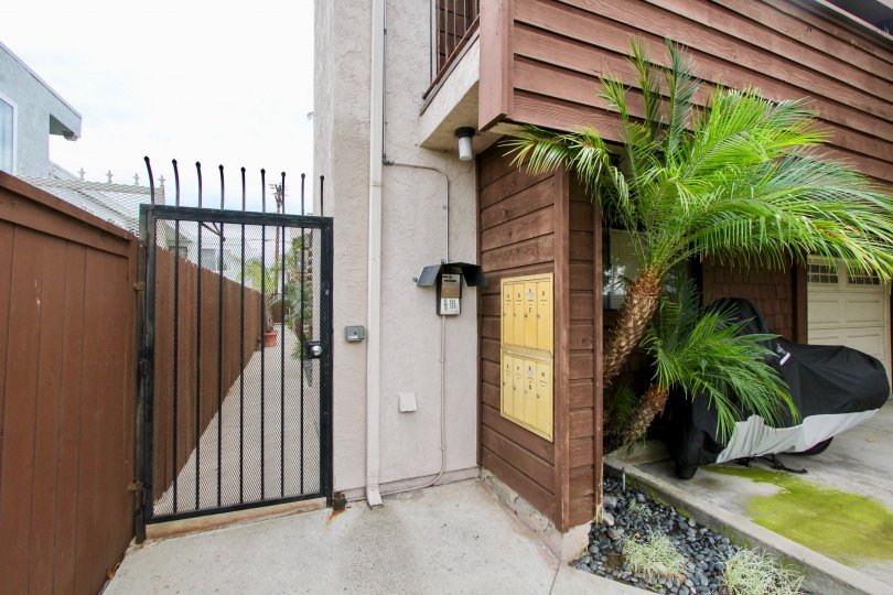 The exterior of Idaho Street Condominiums showing the gated enteryways palm trees and garage door