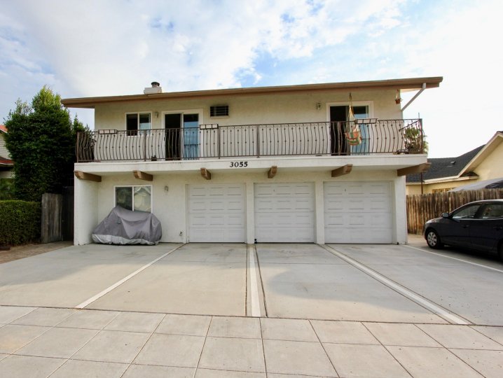 Two sliding glass doors sit open on the second floor of a white apartment building over looking a parking lot in the South Park Villas in North Park California
