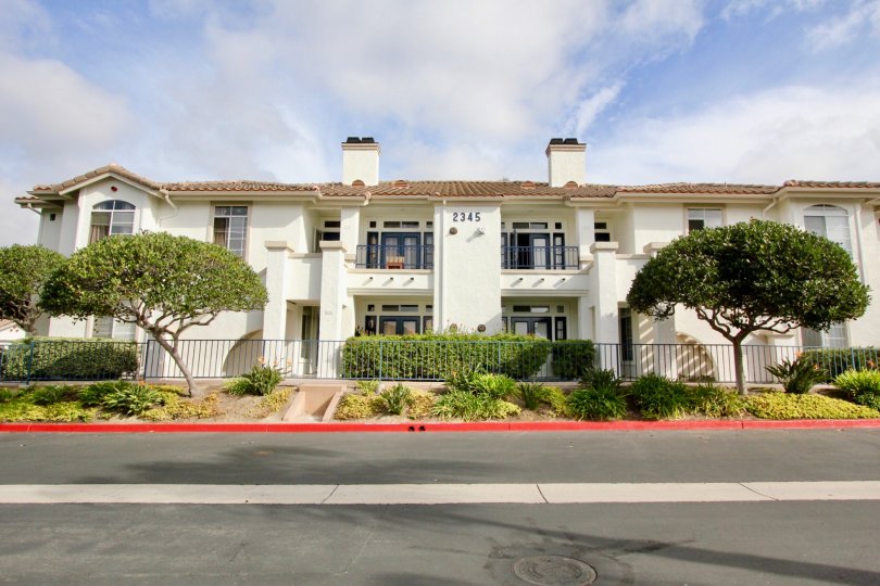 The view across the street of trees and shrubbery in front of Mission Del Oro in Oceanside, CA