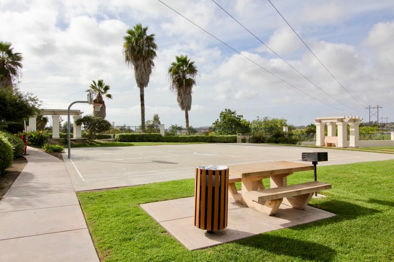 Trash can near a lunch table & basketball court inside the Mission Del Oro at Oceanside CA