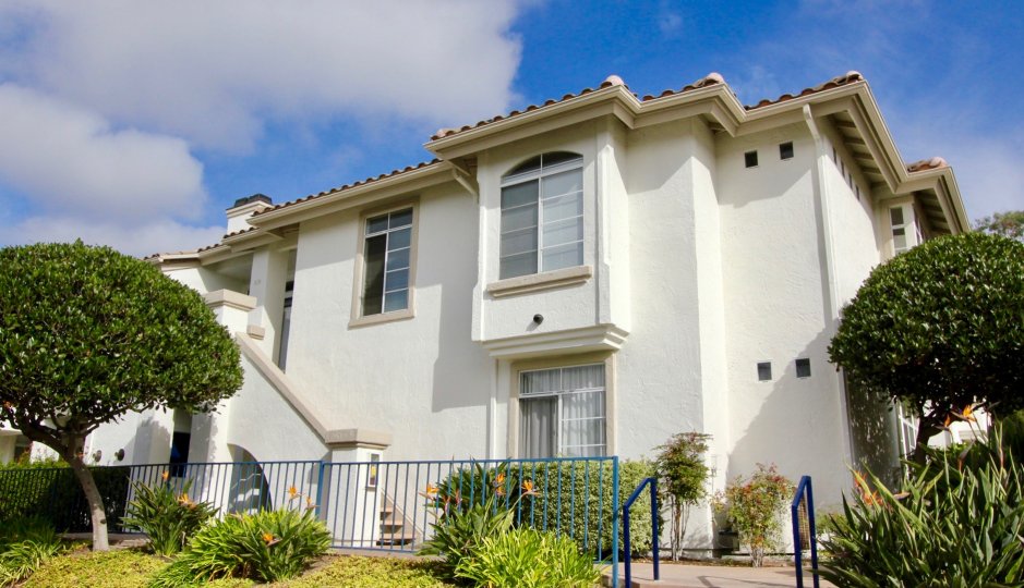 Beige building with large windows and lush lawn at Mission Del Oro in Oceanside, California