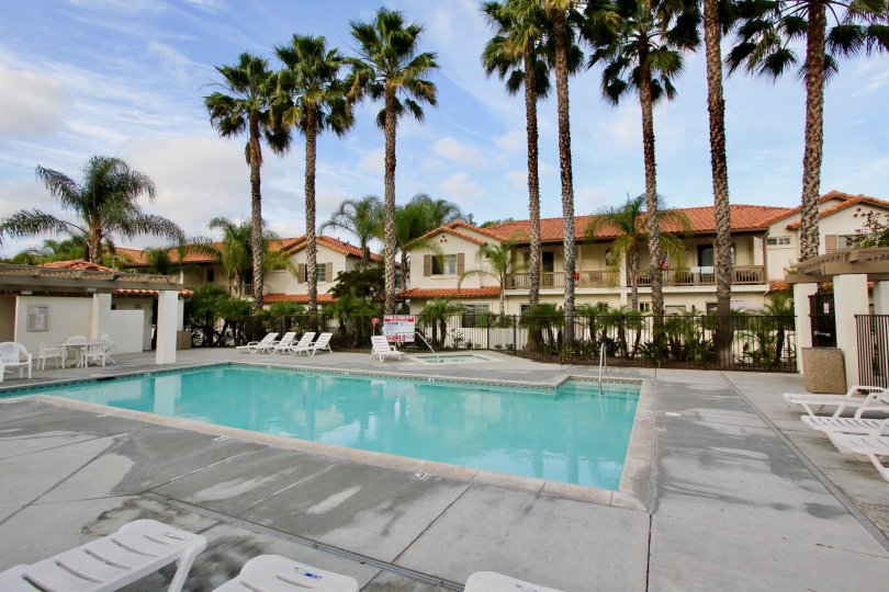 Pool next to condo building in the Rancho Rose community of Oceanside, surrounded by white chairs