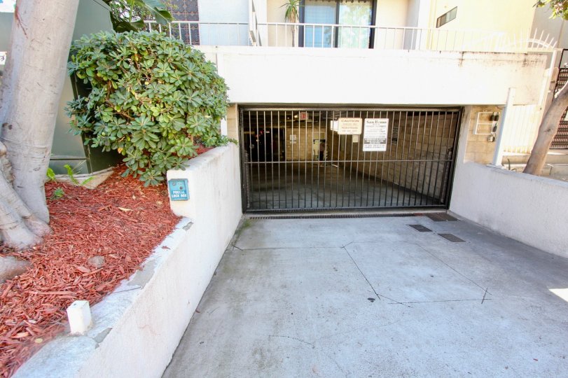 A driveway with a black fence with white colored walls for the rest of the home.