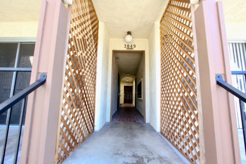 A hallway down a part of brown colored border near a railing.