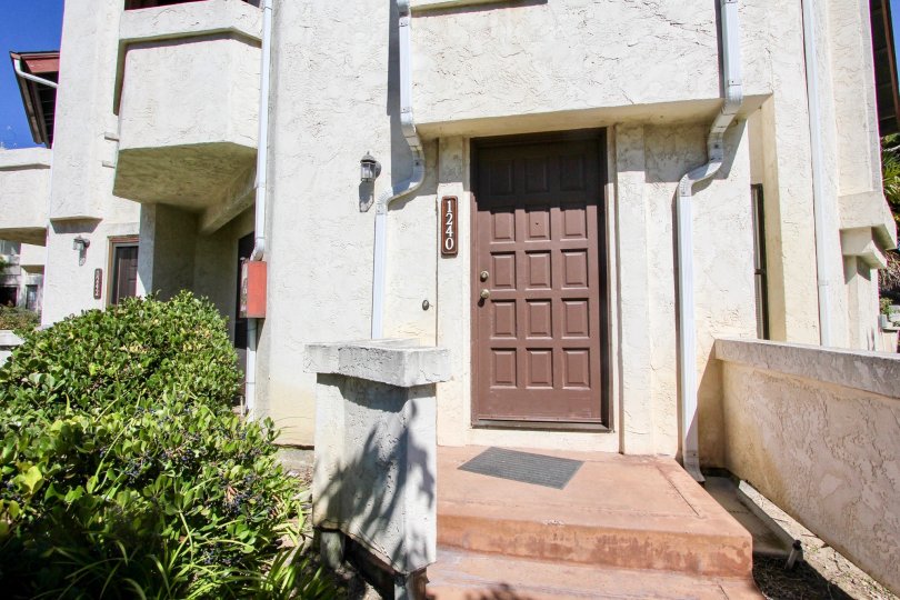 An entrance to the Thomas townhomes with brown front door and concrete railings.