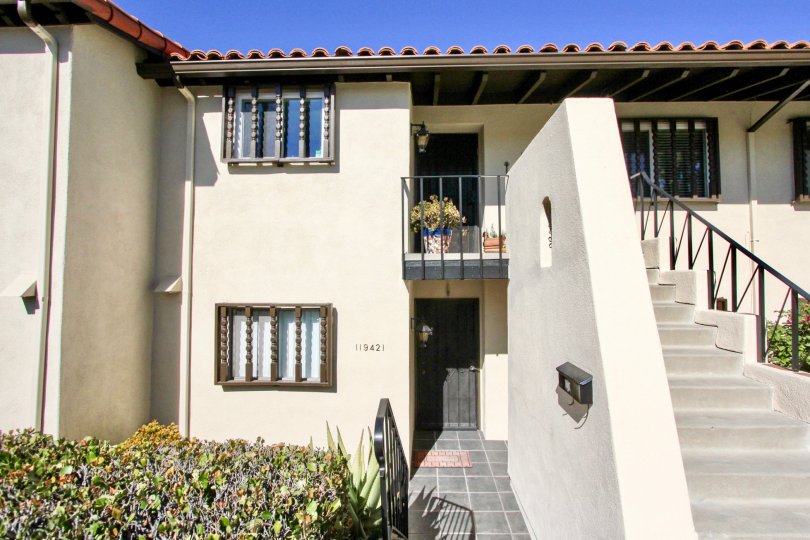 A house with an outdoor staircase and some bushes in the front during a sunny day in Bernardo Villas, Rancho Bernardo, CA