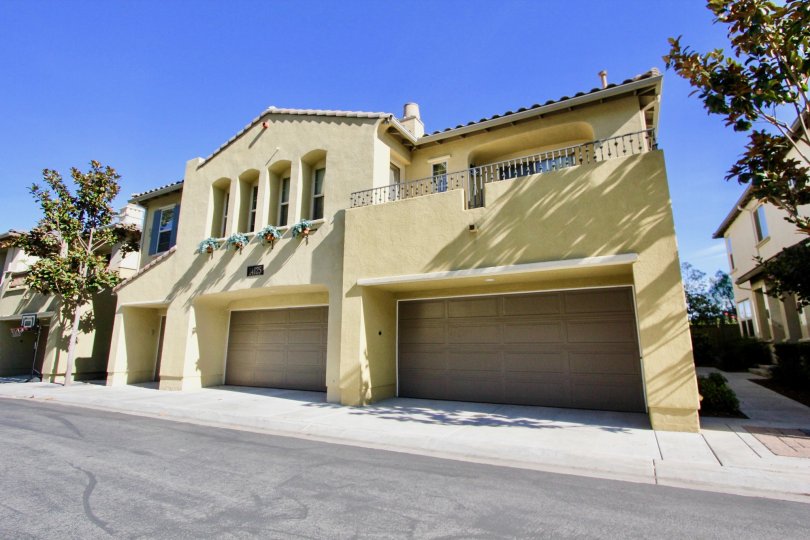 A yellow Spanish style house with two garage doors during a sunny day in Cypress Greens, Rancho Bernardo, CA