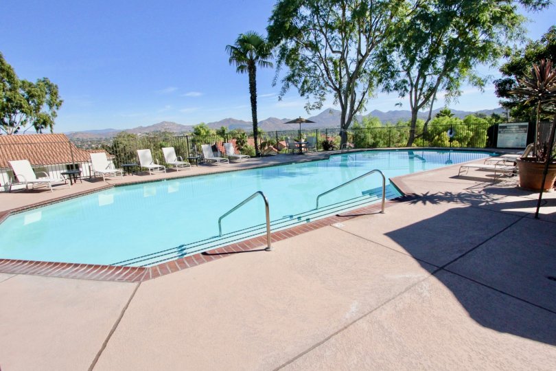 A swimming pool with some trees and a view of the mountains in the background during a sunny day in Lomas Bernardo, Rancho Bernardo, CA