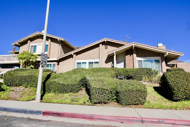 Single story home with large green shrubs inside Playmor in Rancho Bernardo CA