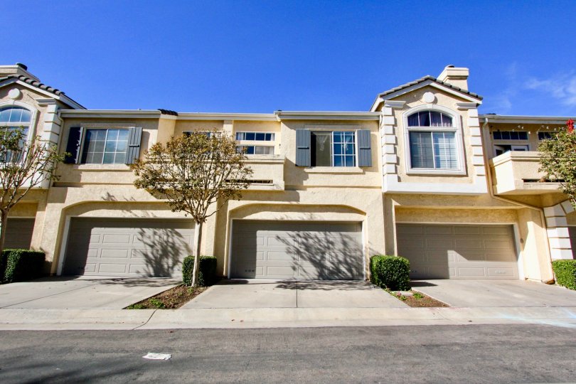 Two story housing with gray garage doors and trees at Provencal in Rancho Bernardo CA