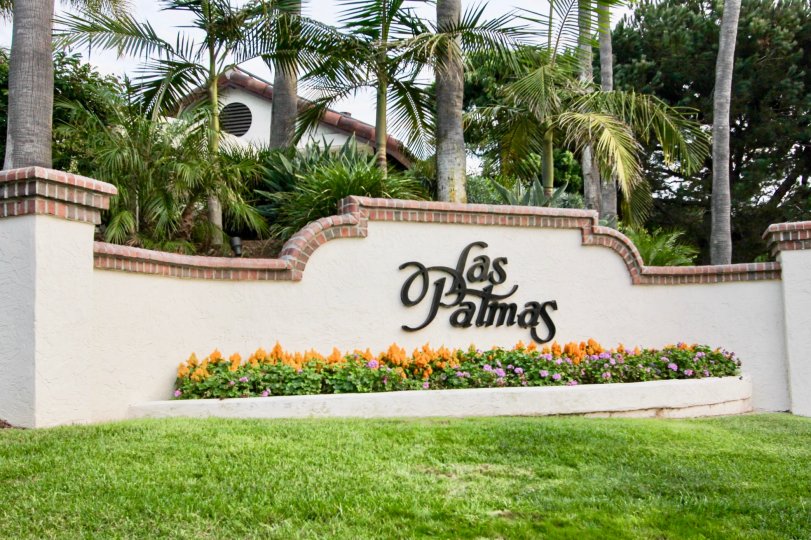 The entry sign with tropical landscaping, palm trees and flowers at Las Palmas in University City, California